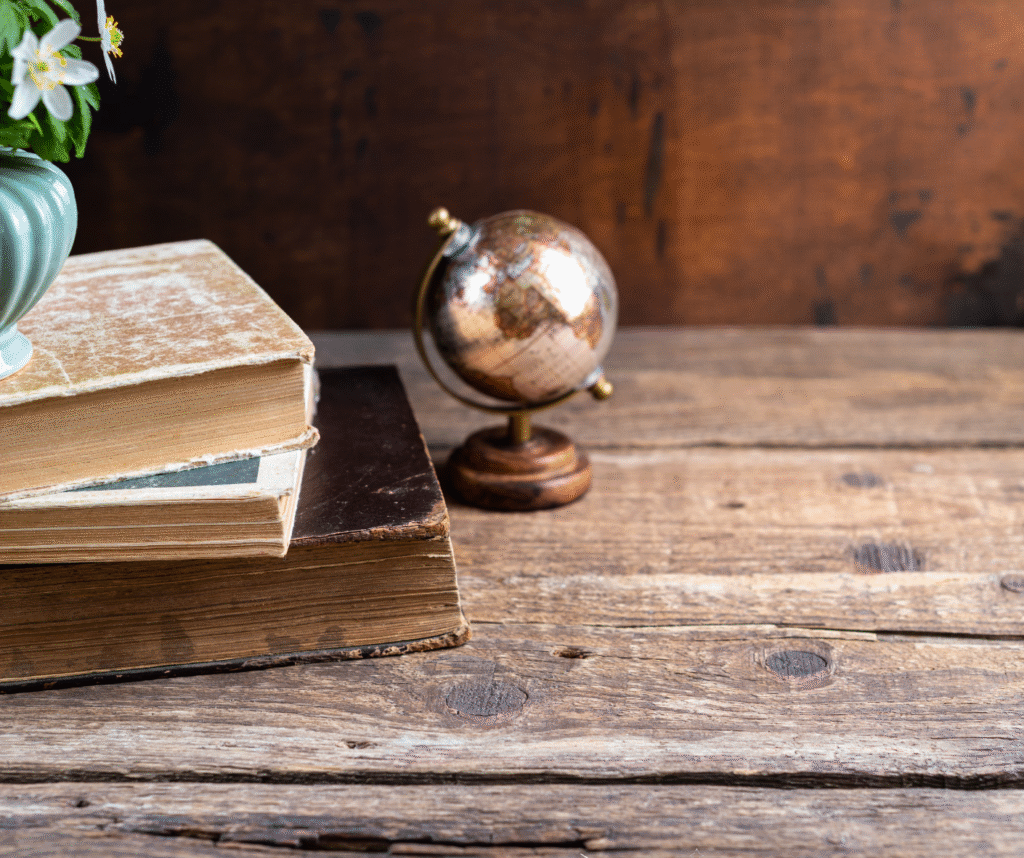 Stare książki i globus na drewnianym stole – literatura o śmierci i odchodzeniu